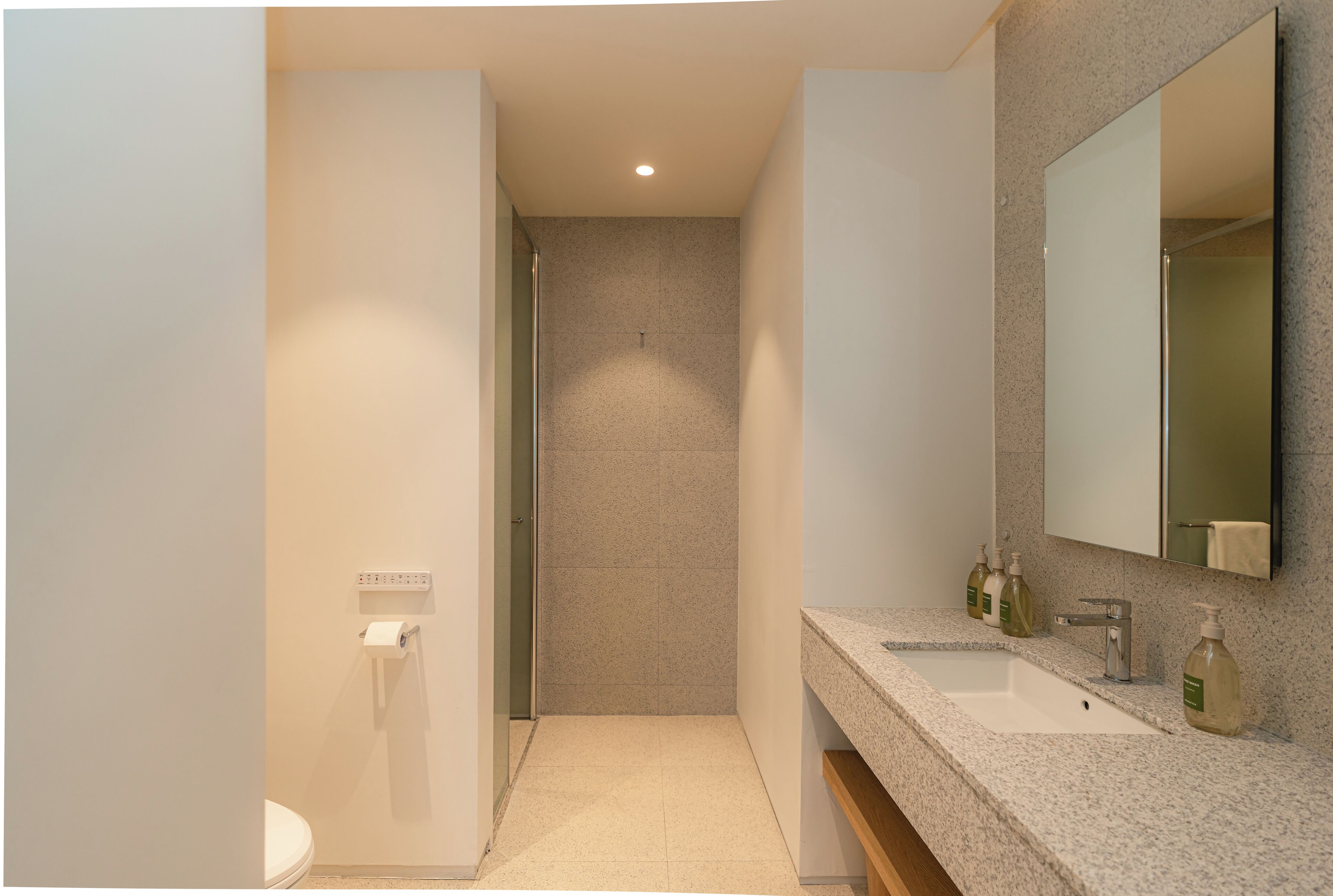 A modern bathroom with a shower, toilet, and sink.