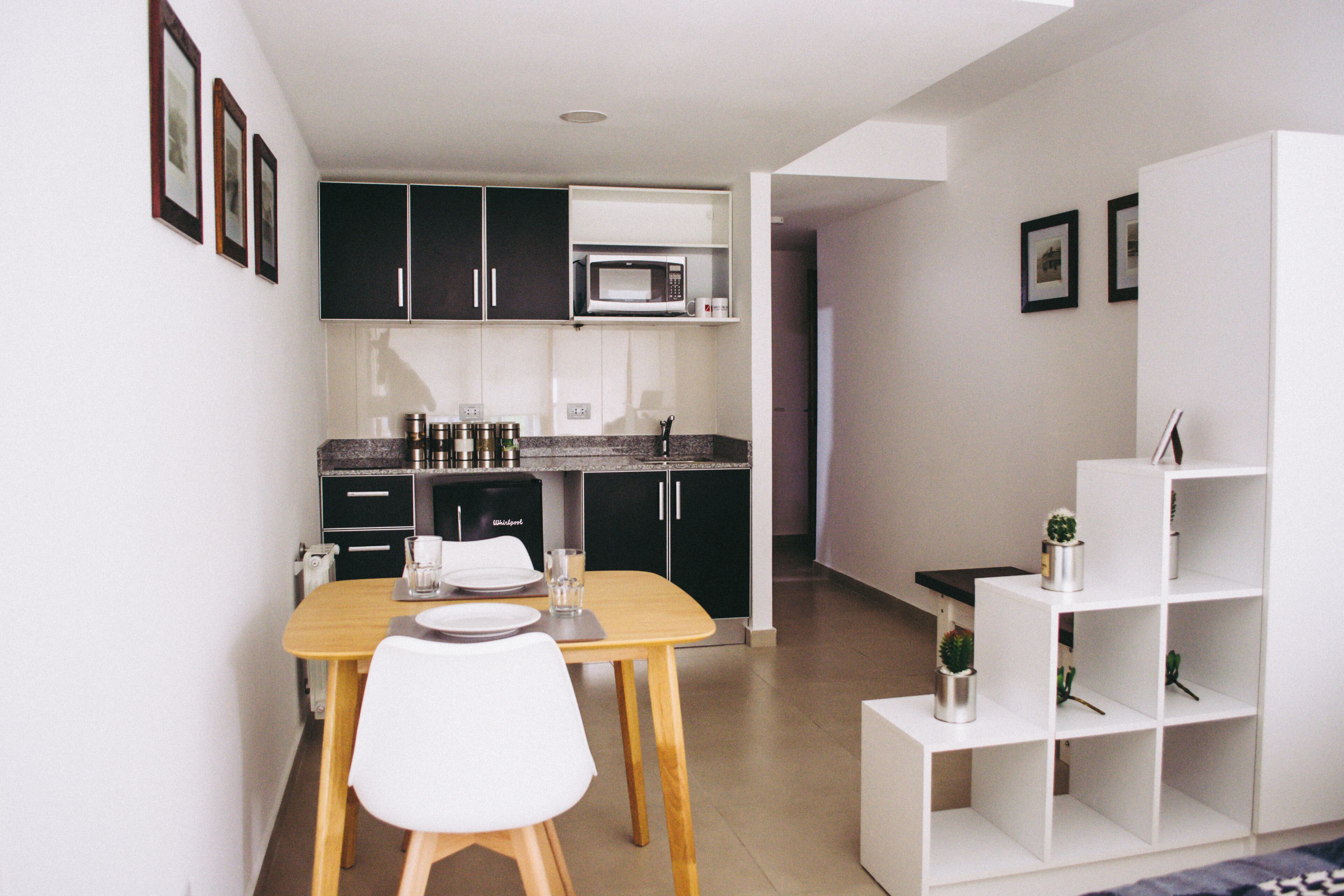 A compact kitchen with dark cabinets, a microwave, and a dining area with a table and chairs.