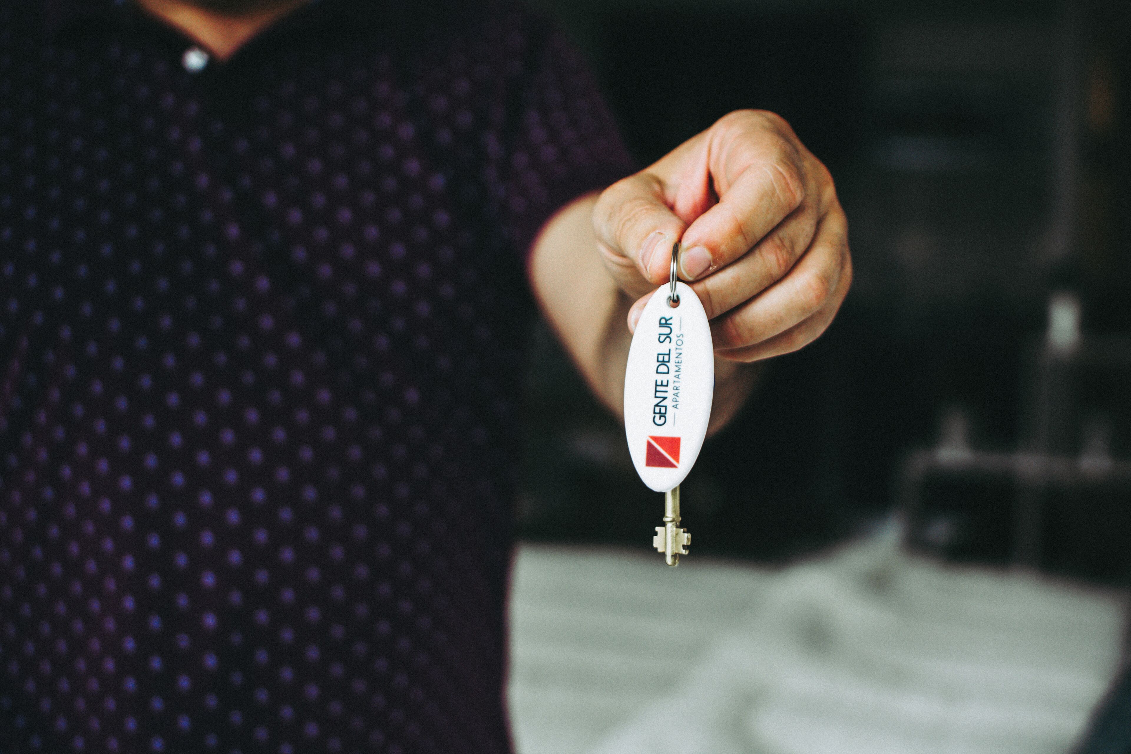A person holding a key with the text "GENDE DEL SUR" and a logo.