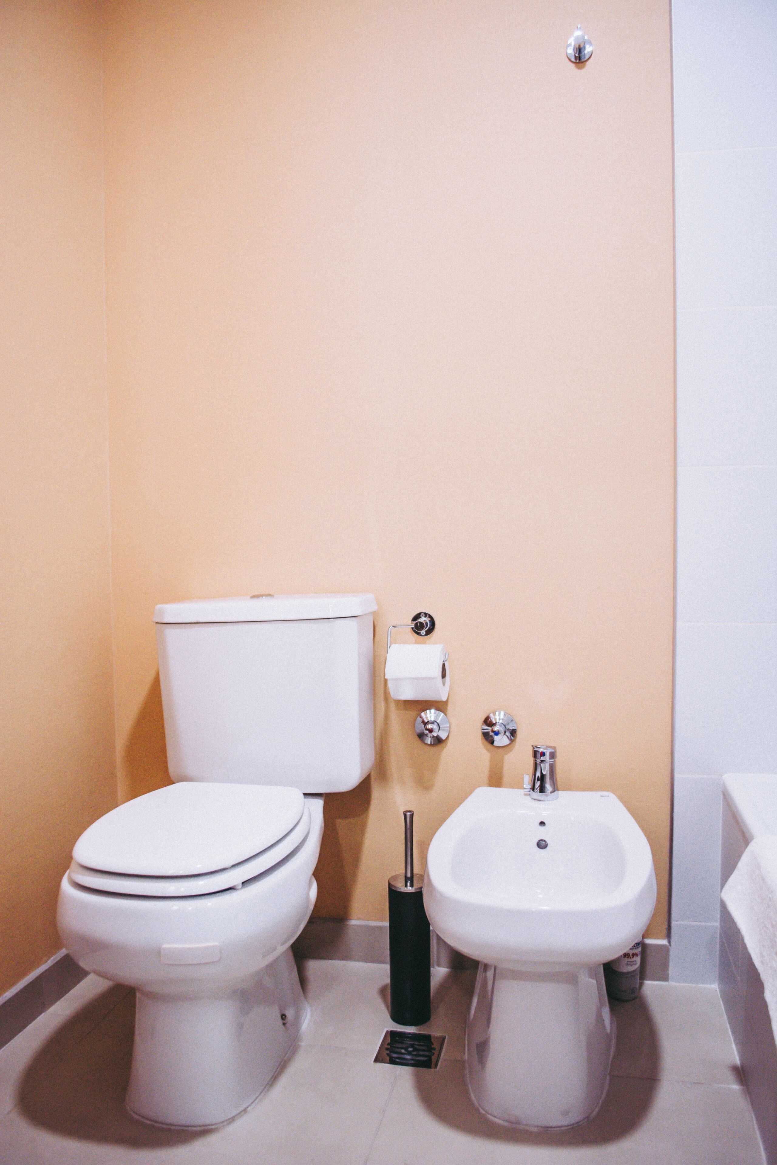 Un baño con inodoro, bidé y un perchero para toallas.