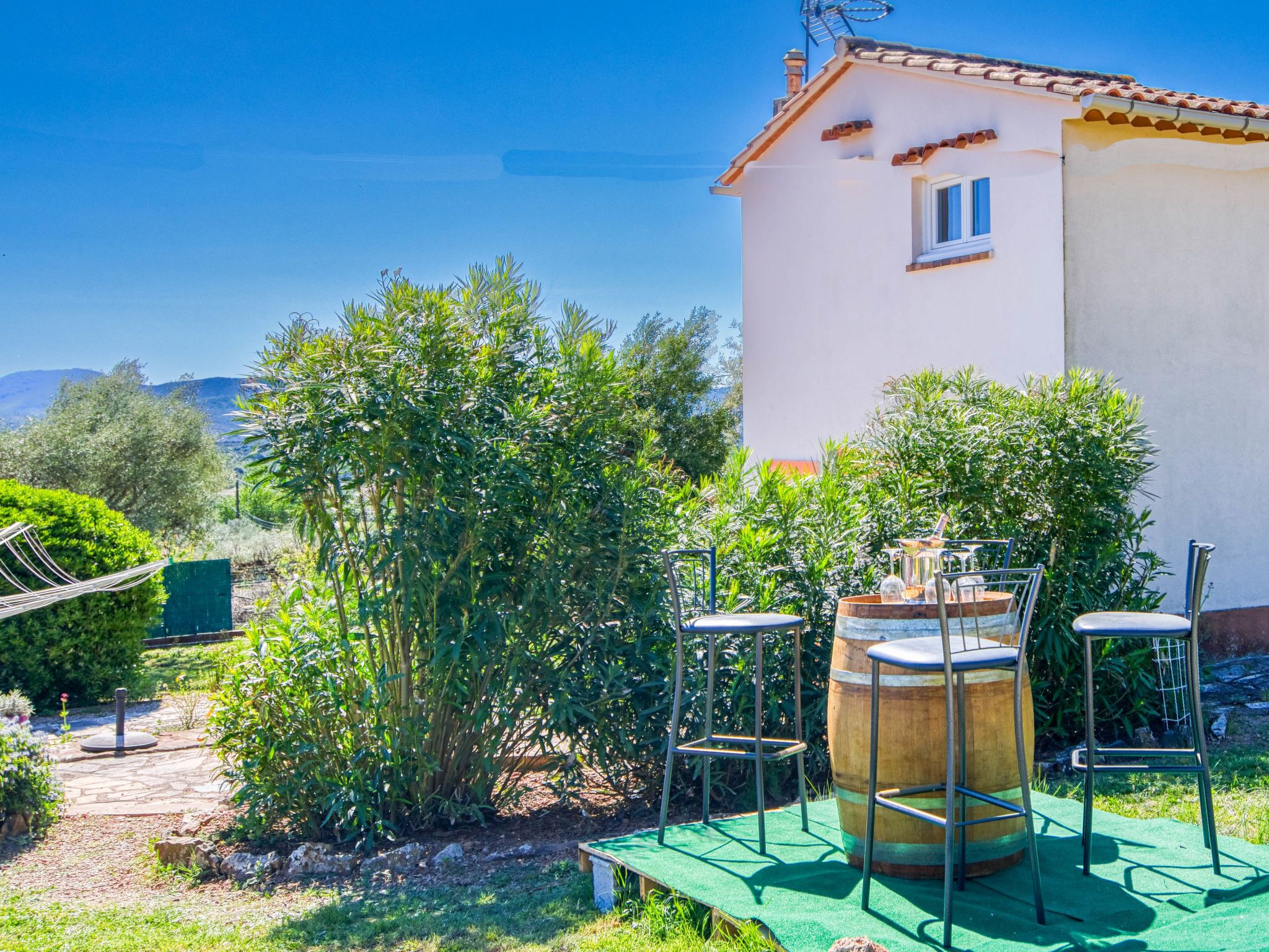 Ein Haus mit einer Terrasse, die Gartenmöbel und ein Fass zeigt.