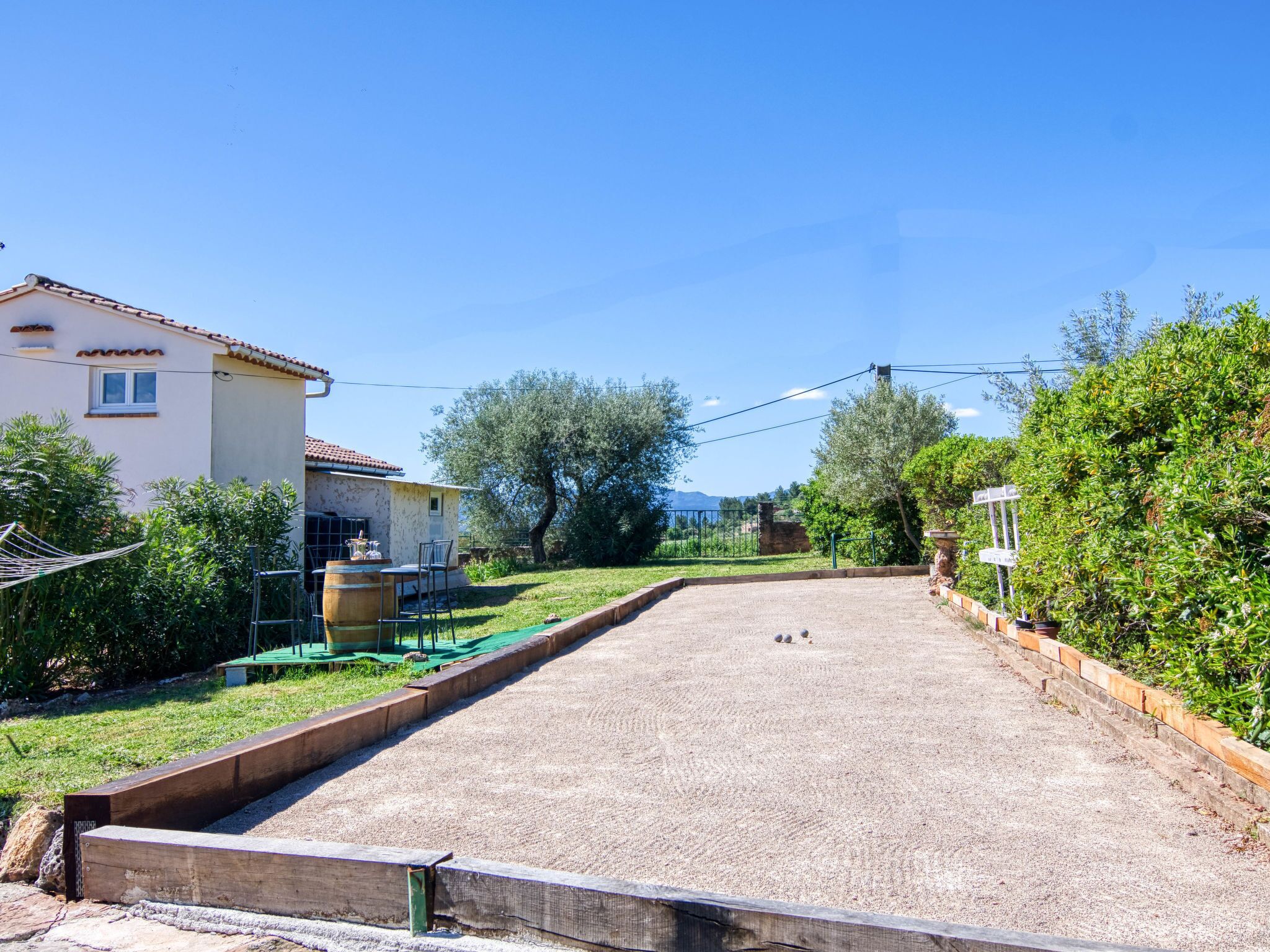 Una strada residenziale con una casa sul lato sinistro, un vialetto sterrato e un prato verde.