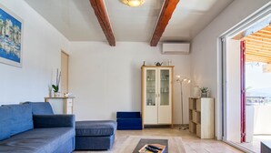 Ein Wohnzimmer mit Sofa, Couchtisch, Schrank und Blick durch eine Glastür.