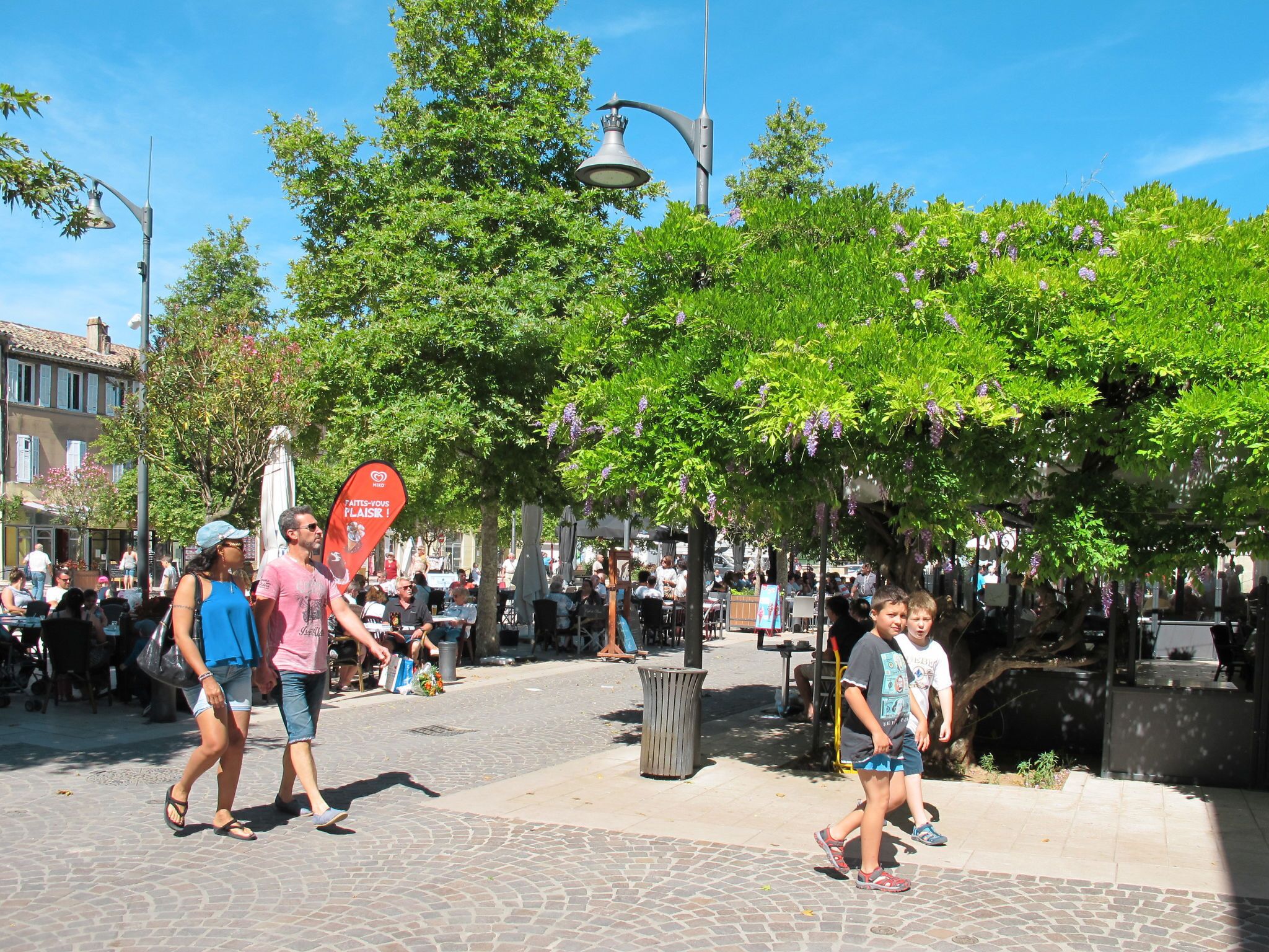 Una calle adoquinada con peatones, árboles y zonas de estar al aire libre.