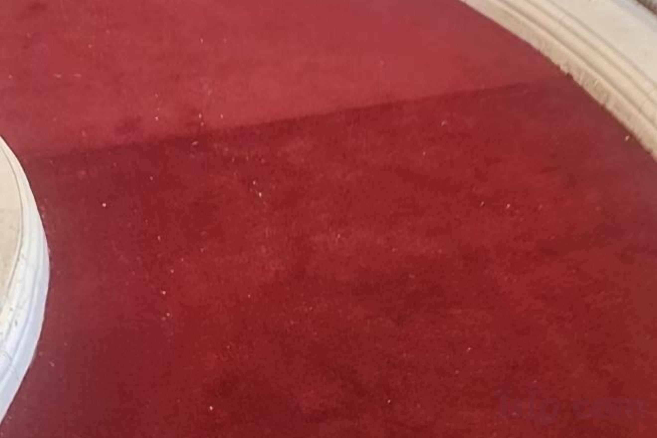 Un área con alfombra roja y un objeto circular blanco, posiblemente una mesa o un adorno, a la izquierda.