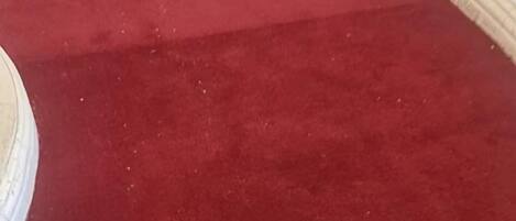 Un área con alfombra roja y un objeto circular blanco, posiblemente una mesa o un adorno, a la izquierda.