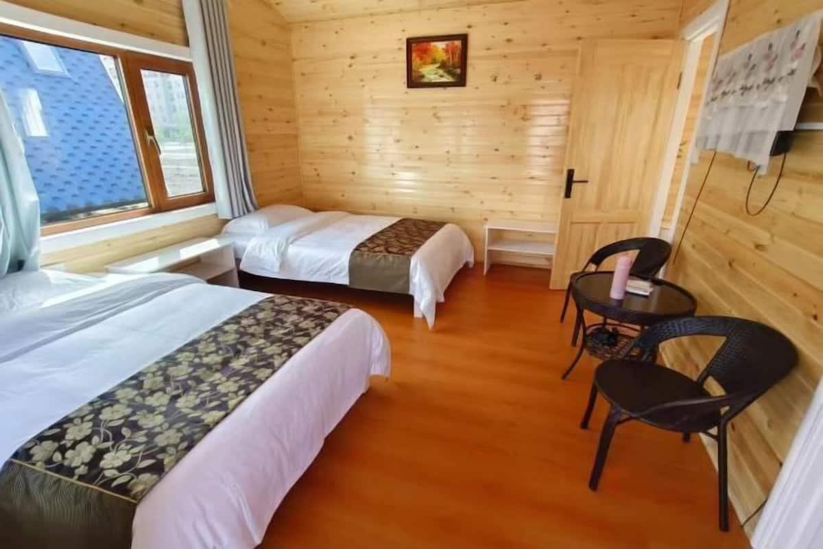 A wooden cabin with two beds, a small table, and chairs.