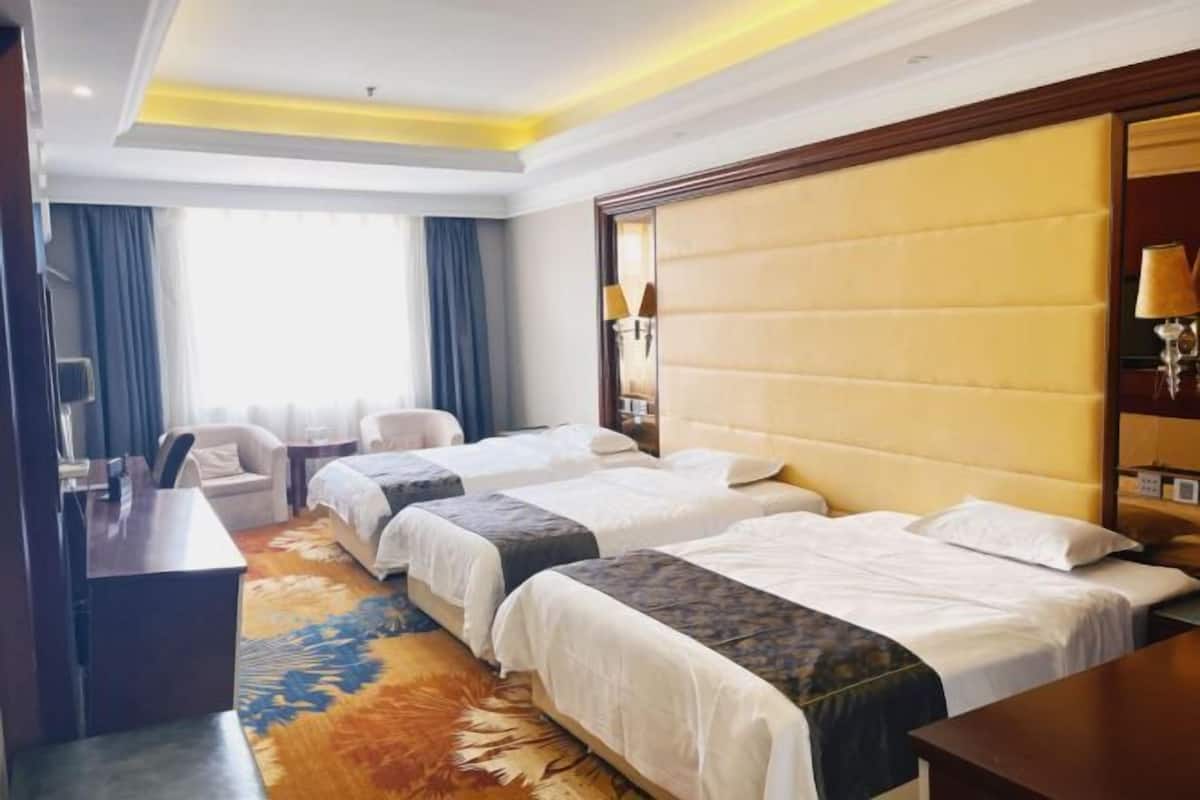 A hotel room with two beds, a desk, a chair, and a large window with curtains.