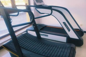 A treadmill with a digital display, positioned near a window with a view of the outdoors.