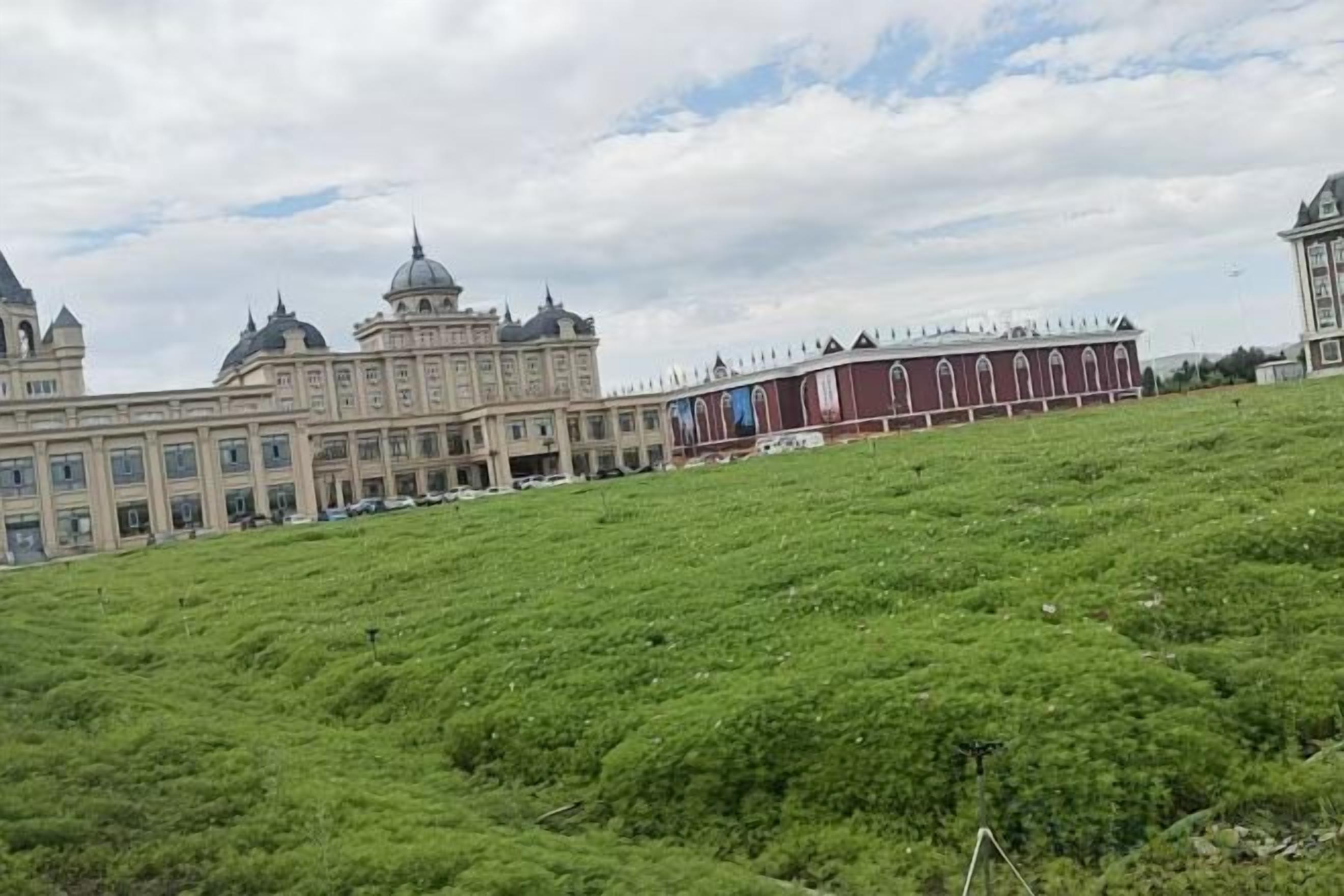 Ein großes Gebäude mit mehreren Kuppeln und einer roten Struktur auf einem grasbewachsenen Hügel.