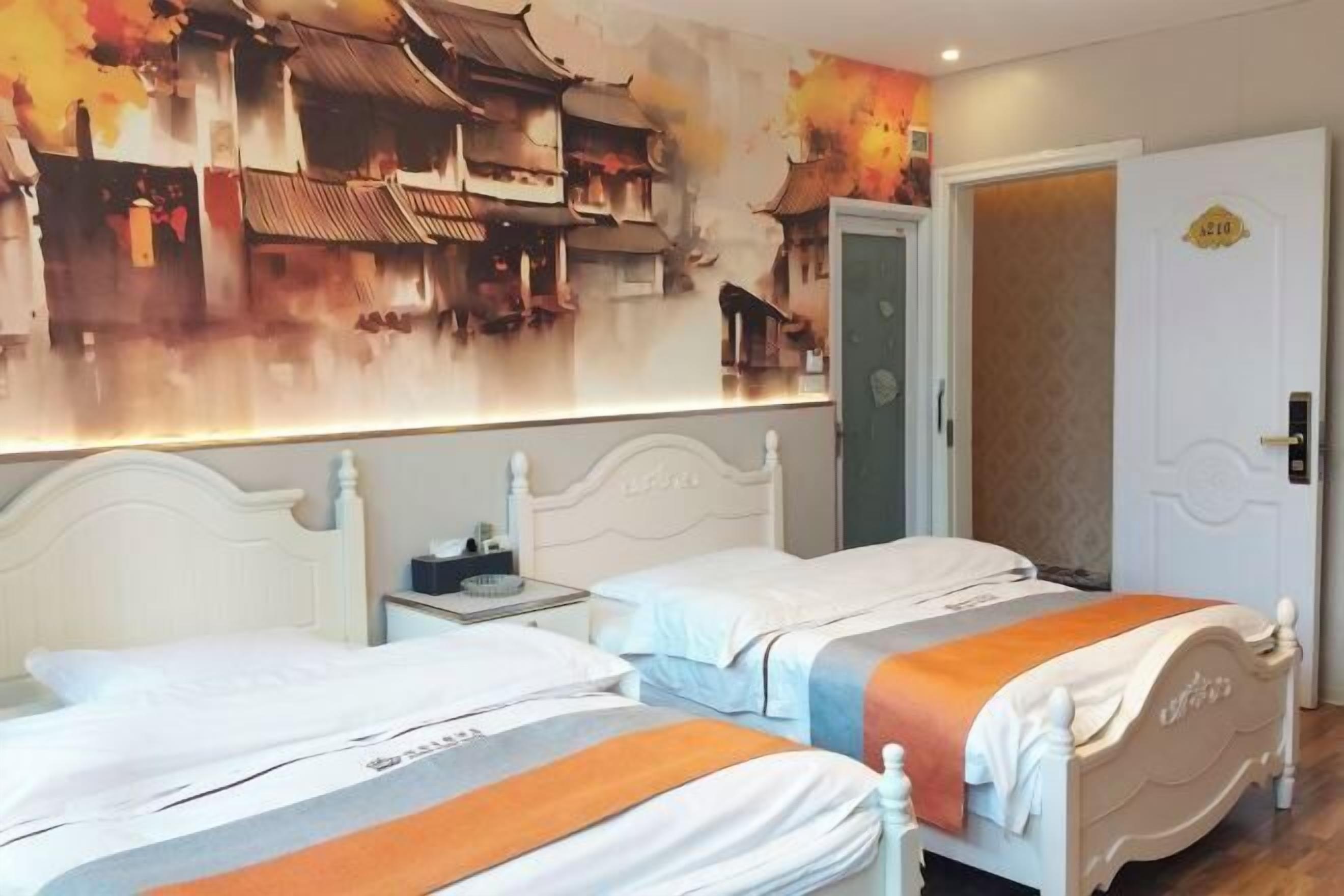 A hotel room with two beds, a nightstand, a wall mural, and a door with a number plate.