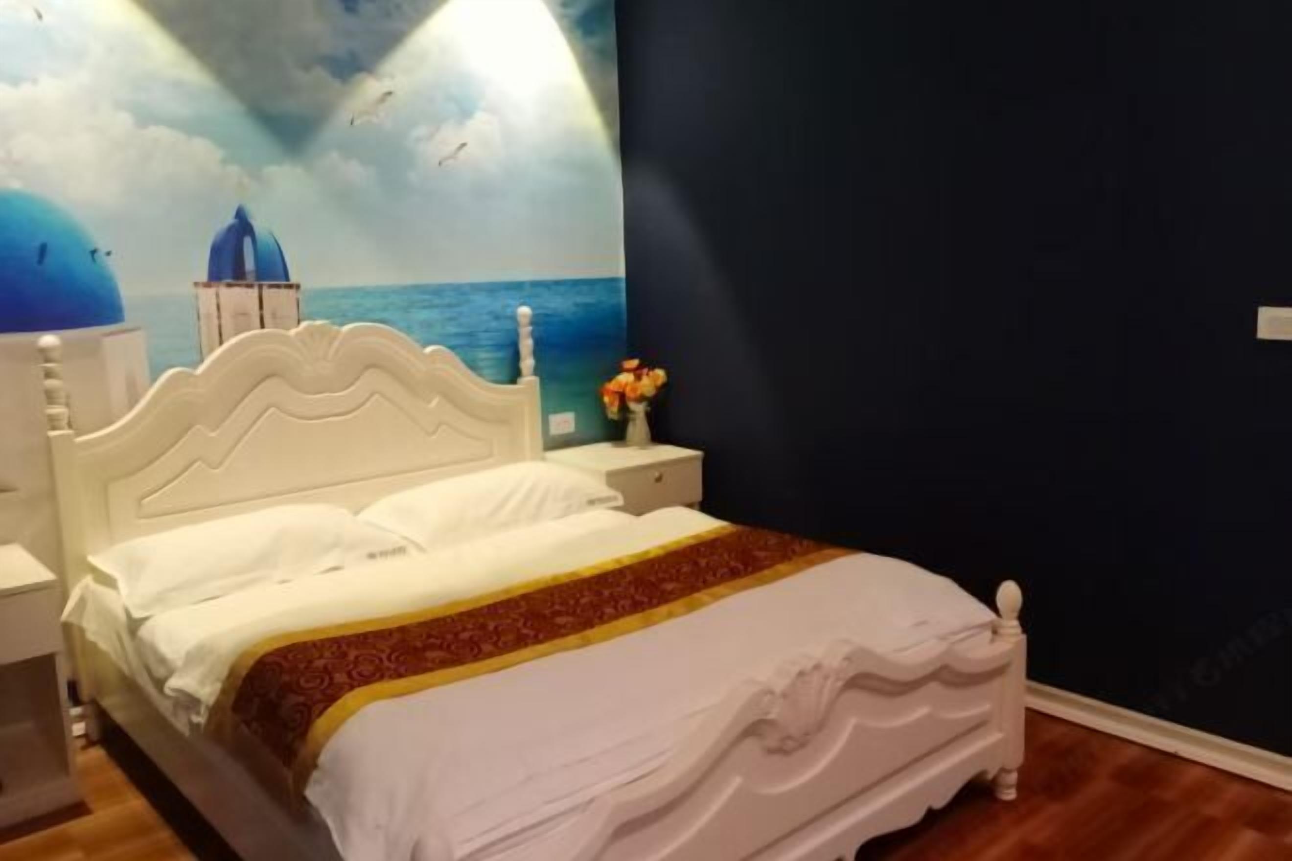 A bedroom with a bed, nightstands, a wall mural, and a vase with flowers.