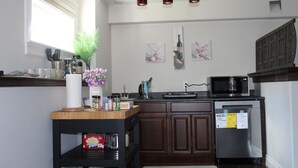 Uma cozinha moderna com armários de madeira, uma geladeira de aço inoxidável, um micro-ondas e uma bancada de madeira.