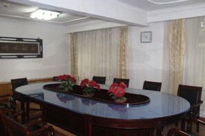 A conference room with a large oval table, chairs, and a clock on the wall. - Red Mansion Guest House Beijing (Beijing)