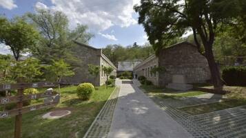 A pathway leading to stone buildings with a signpost on the left.