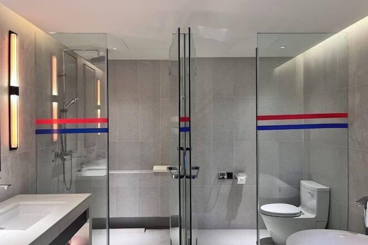 A modern bathroom with a glass shower enclosure, a white sink, and a toilet.