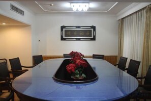 A conference room with a large oval table, chairs, and a floral centerpiece. - Red Mansion Guest House Beijing (Beijing)