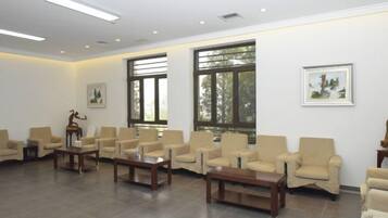 A spacious room with multiple seating areas, large windows, and artwork on the walls.