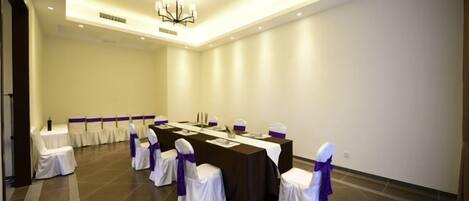 Un salón de conferencias con una larga mesa, sillas y una lámpara de araña.