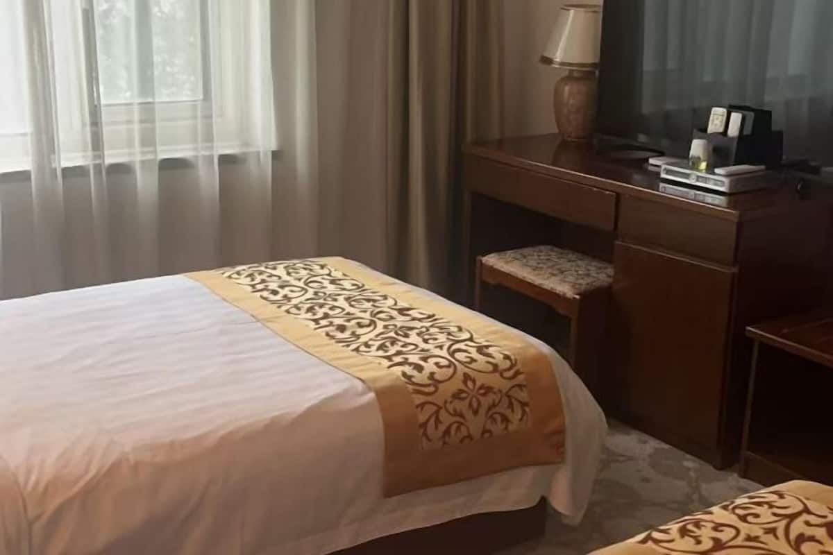A hotel room with a bed, a desk, and a chair.