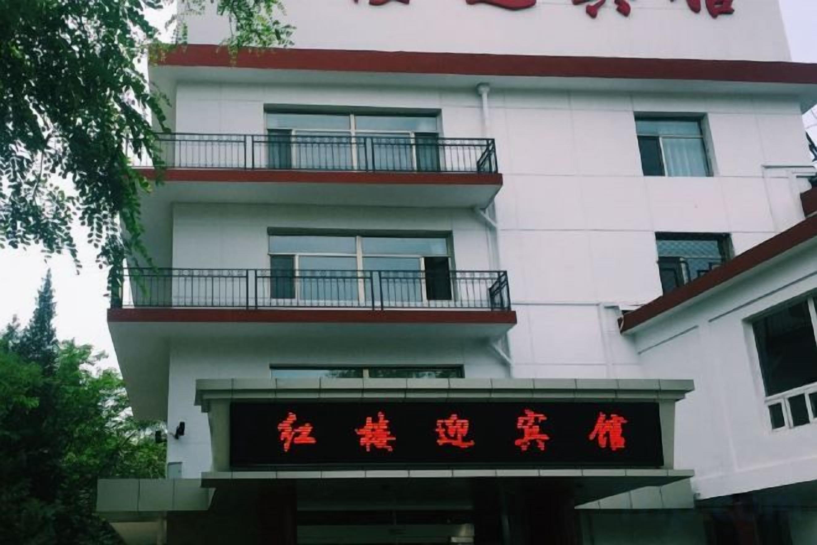 Un edificio de varios pisos con un letrero que dice '红楼迎宾馆' (Honglou Welcome Hotel).