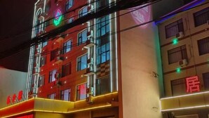 A building with multiple floors, large windows, and neon signage. - jujia lianhe jiudian (Boye)