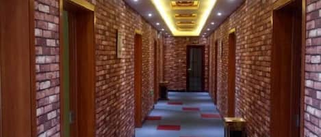 A hallway with brick walls and doors, carpeted floor, and recessed lighting.