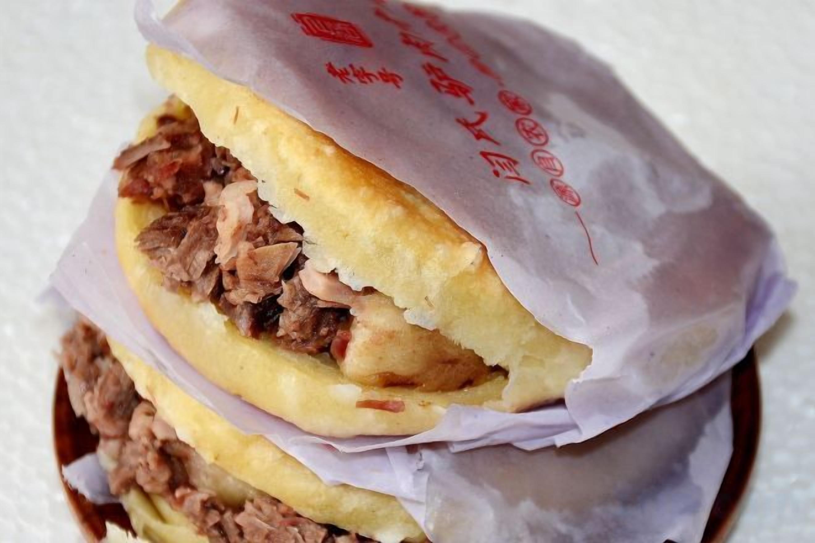 A sandwich with visible fillings, wrapped in paper with text.