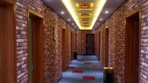 A hallway with brick walls and wooden doors, leading to a room with a bed. - jujia lianhe jiudian (Boye)
