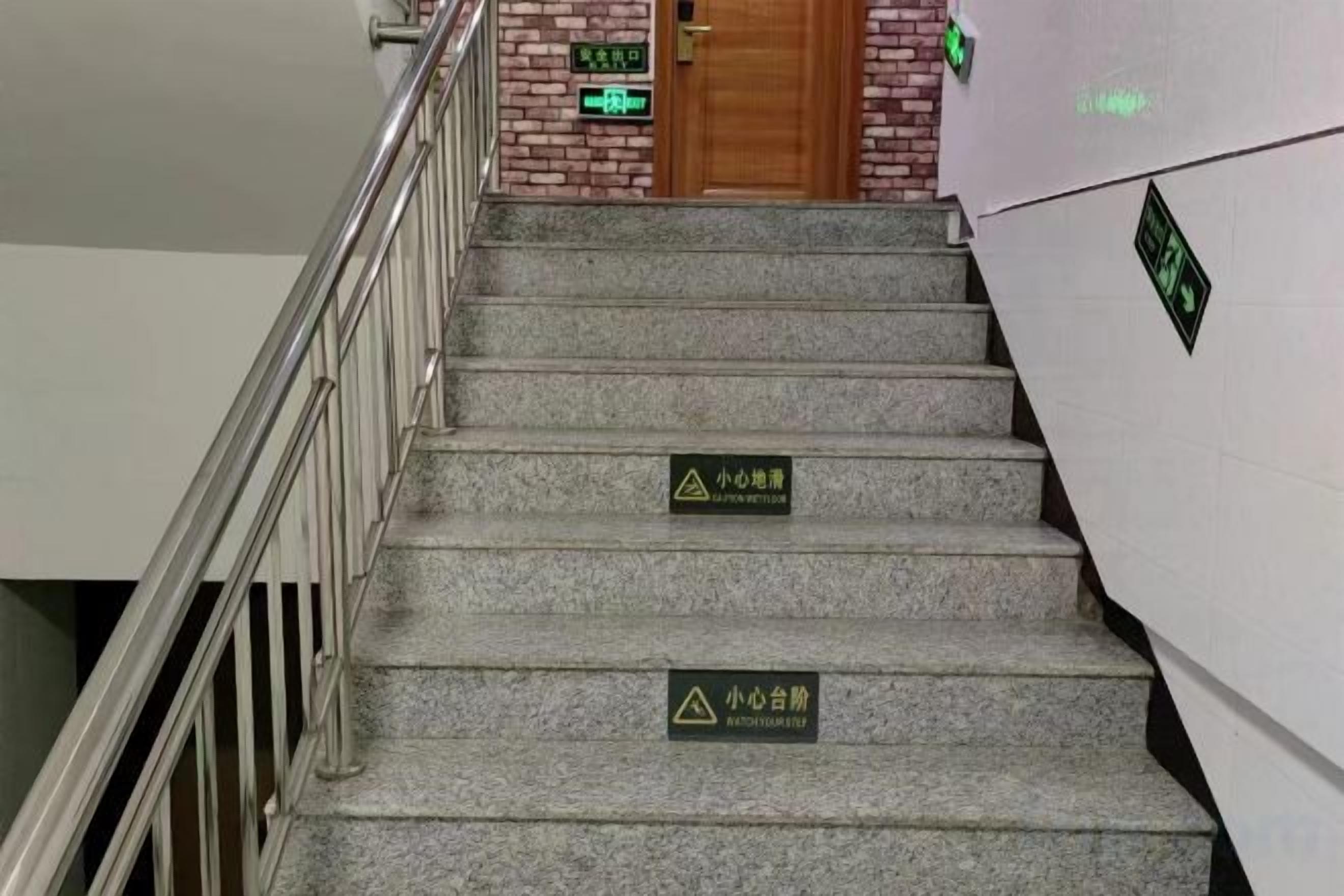 A staircase with handrails and warning signs indicating a wet floor.