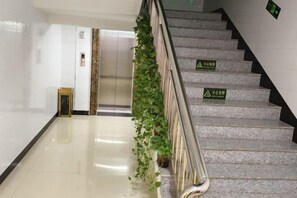 A staircase with handrails and green safety signs, leading to an elevator. - jujia lianhe jiudian (Boye)