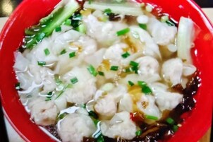 A bowl of soup with meatballs and green onions.