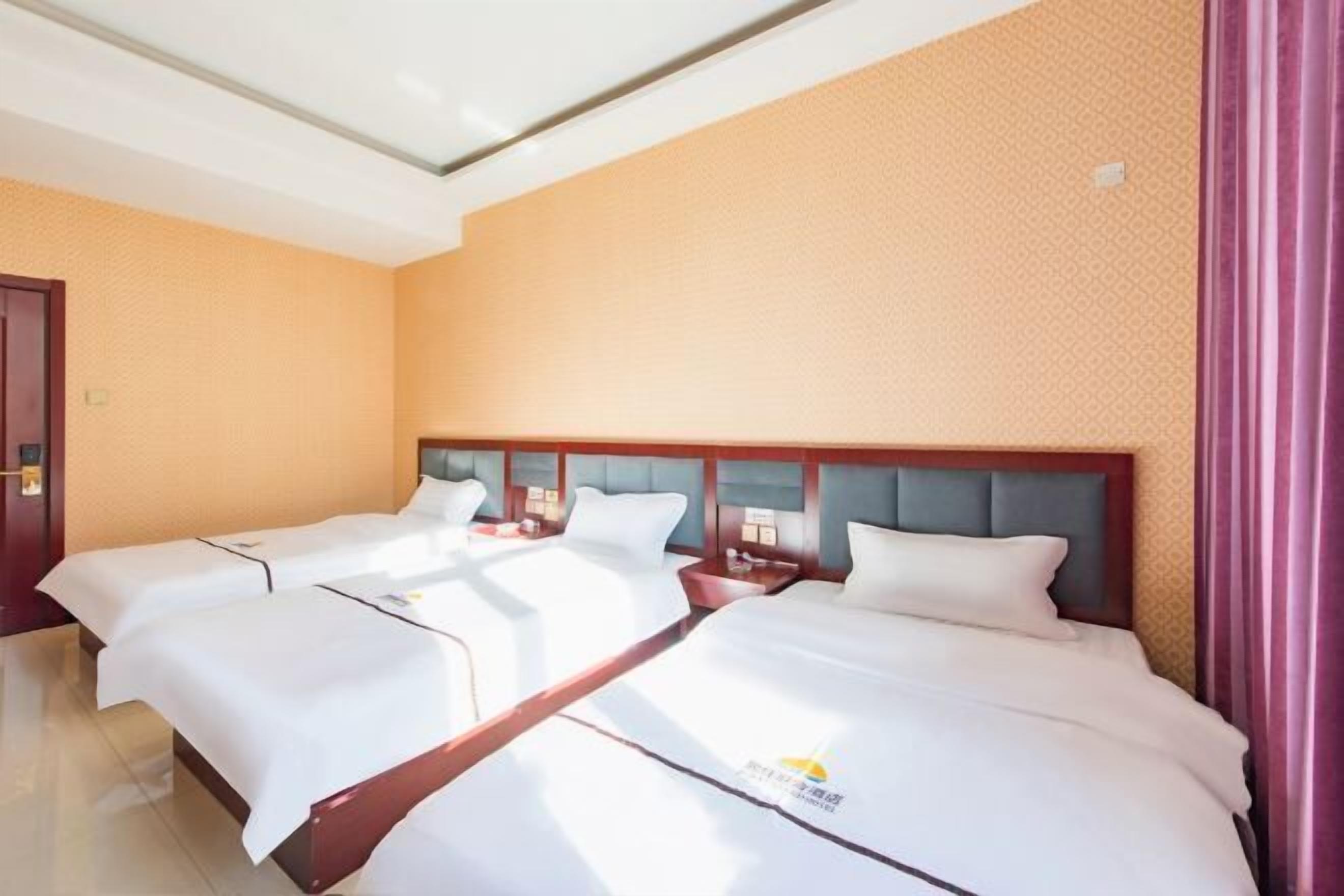 A hotel room with two beds, a wooden headboard, and a patterned wall.