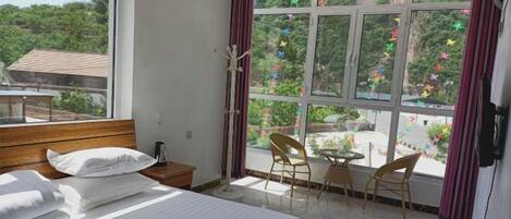 Habitación de hotel con cama, una mesita, dos sillas y una ventana con cortinas.