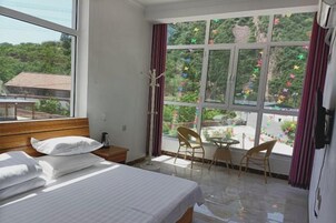Habitación de hotel con cama, una mesita, dos sillas y una ventana con cortinas.