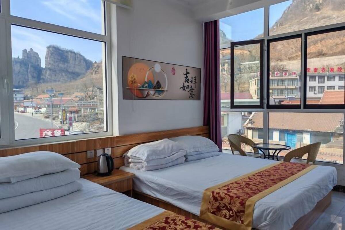A hotel room with two beds, a view of a mountainous landscape, and a painting on the wall.