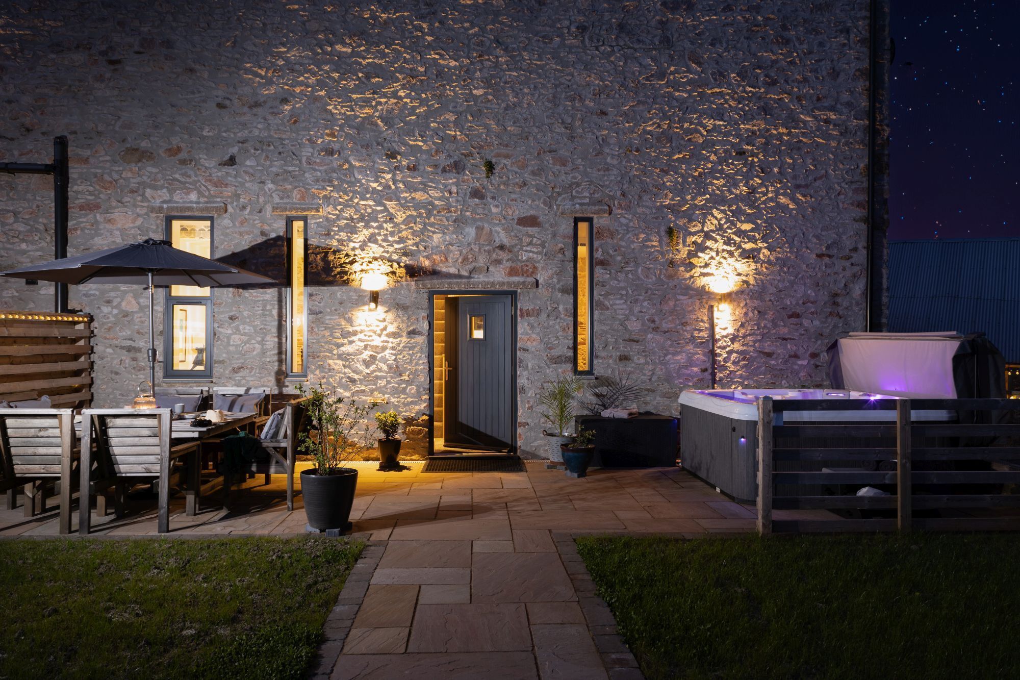 Een gebouw van steen met terras en een hottub.