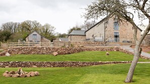 A stone building with a stone wall and a grassy area in front. - One of 3 cottages, this beautiful barn conversion with a hot tub and EV charger is the perfect place (Paignton)