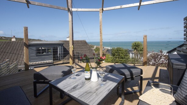 Eine Terrasse mit Tisch, Stühlen und Meerblick.