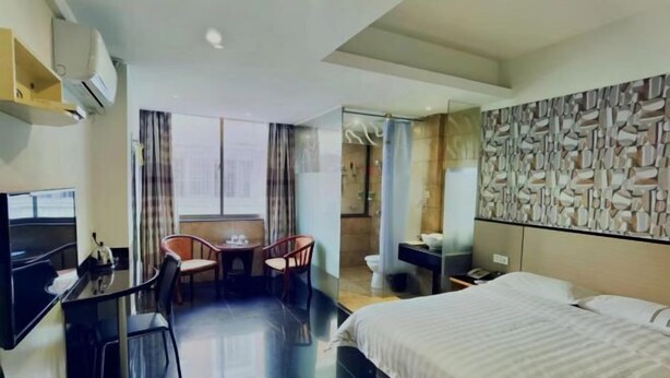 Een hotelkamer met een bed, een bureau, een stoel, een televisie en een badkamer.