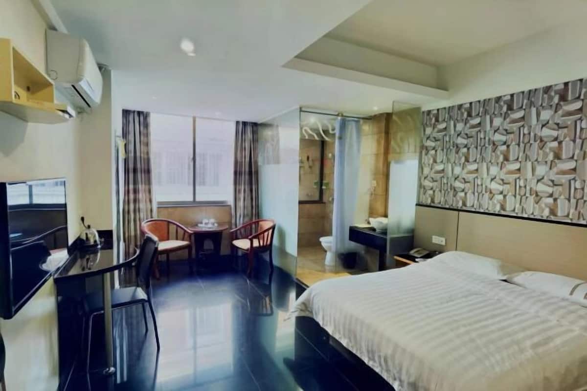 Une chambre d’hôtel comprenant un lit, un bureau, une chaise, une télévision et une salle de bain.