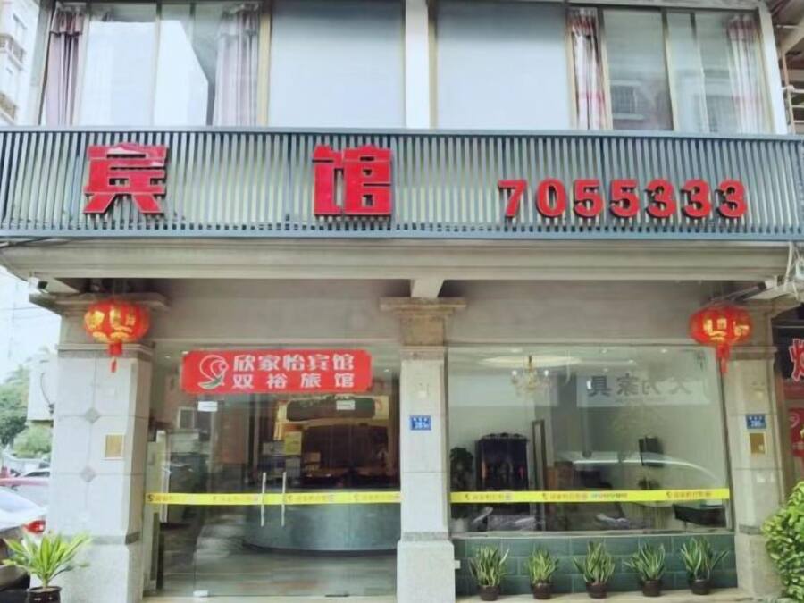 A hotel with a prominent red sign displaying the name and contact number.