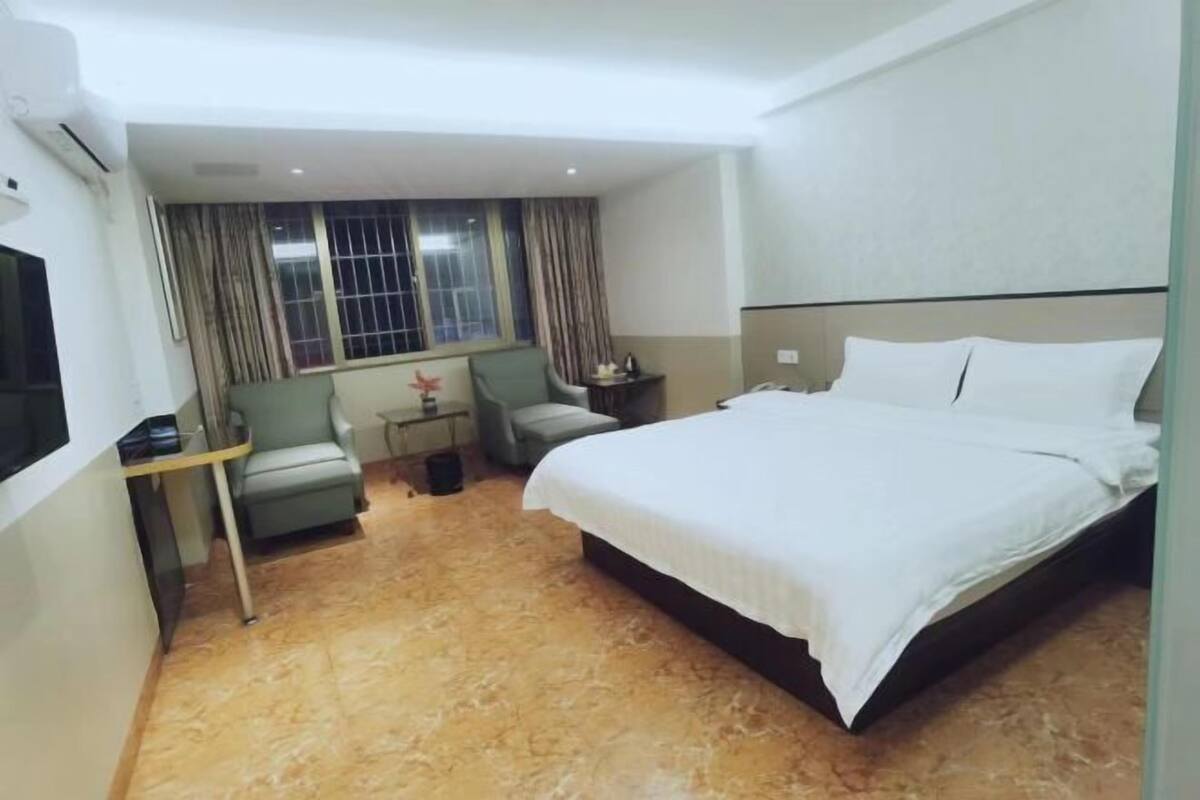 Une chambre d’hôtel avec un lit, un bureau, une chaise et une fenêtre avec des rideaux.