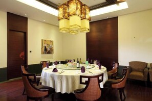 A dining area with a round table, chairs, and a chandelier.