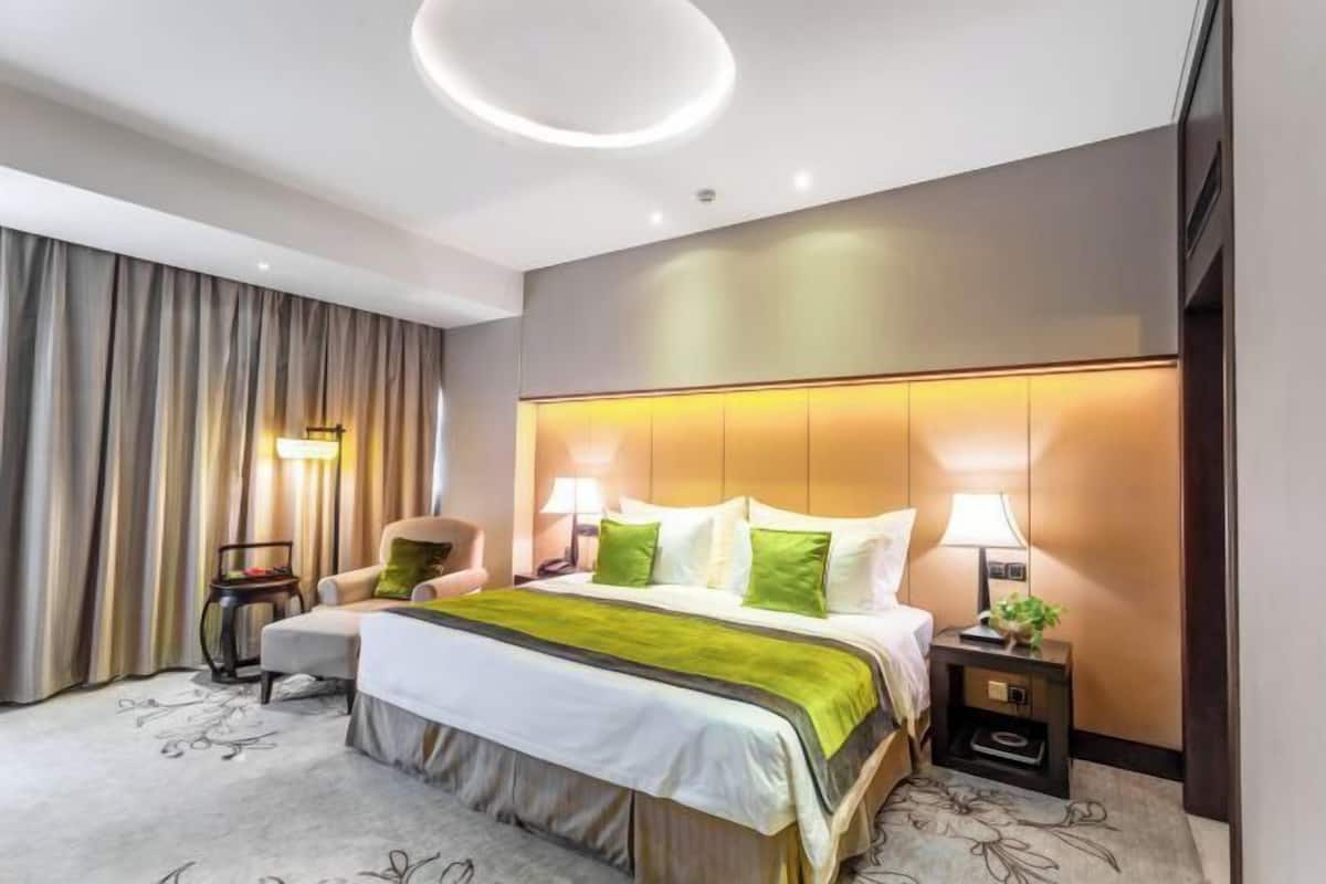 Een moderne hotelkamer met een groot bed, een bureau, een stoel en een nachtkastje.