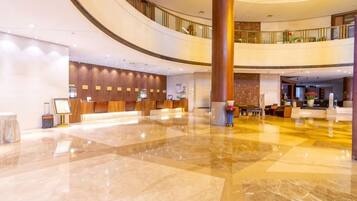 A spacious lobby with a reception desk, seating area, and a large pillar.