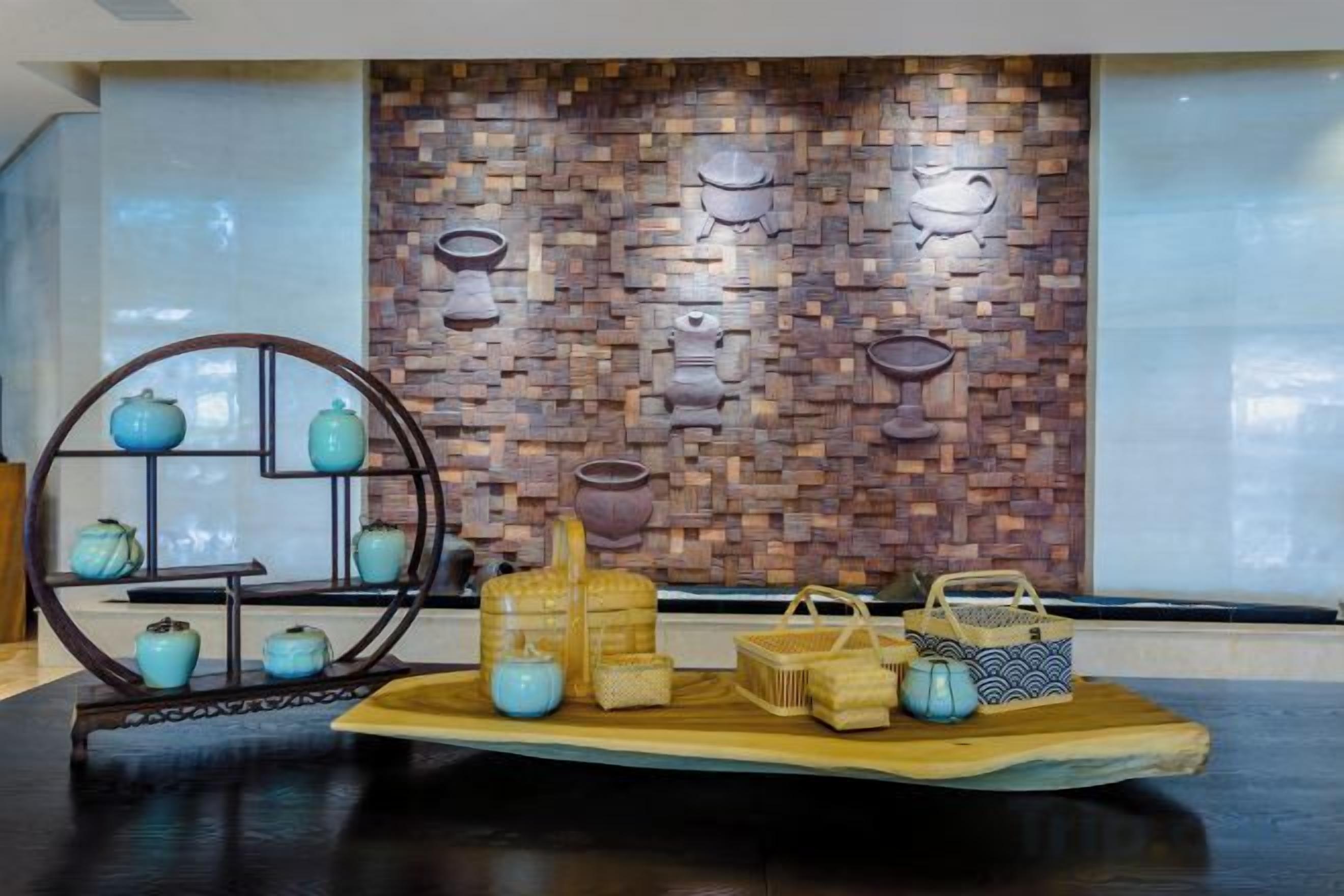 A display of ceramic items on a wooden platform with a brick wall backdrop.