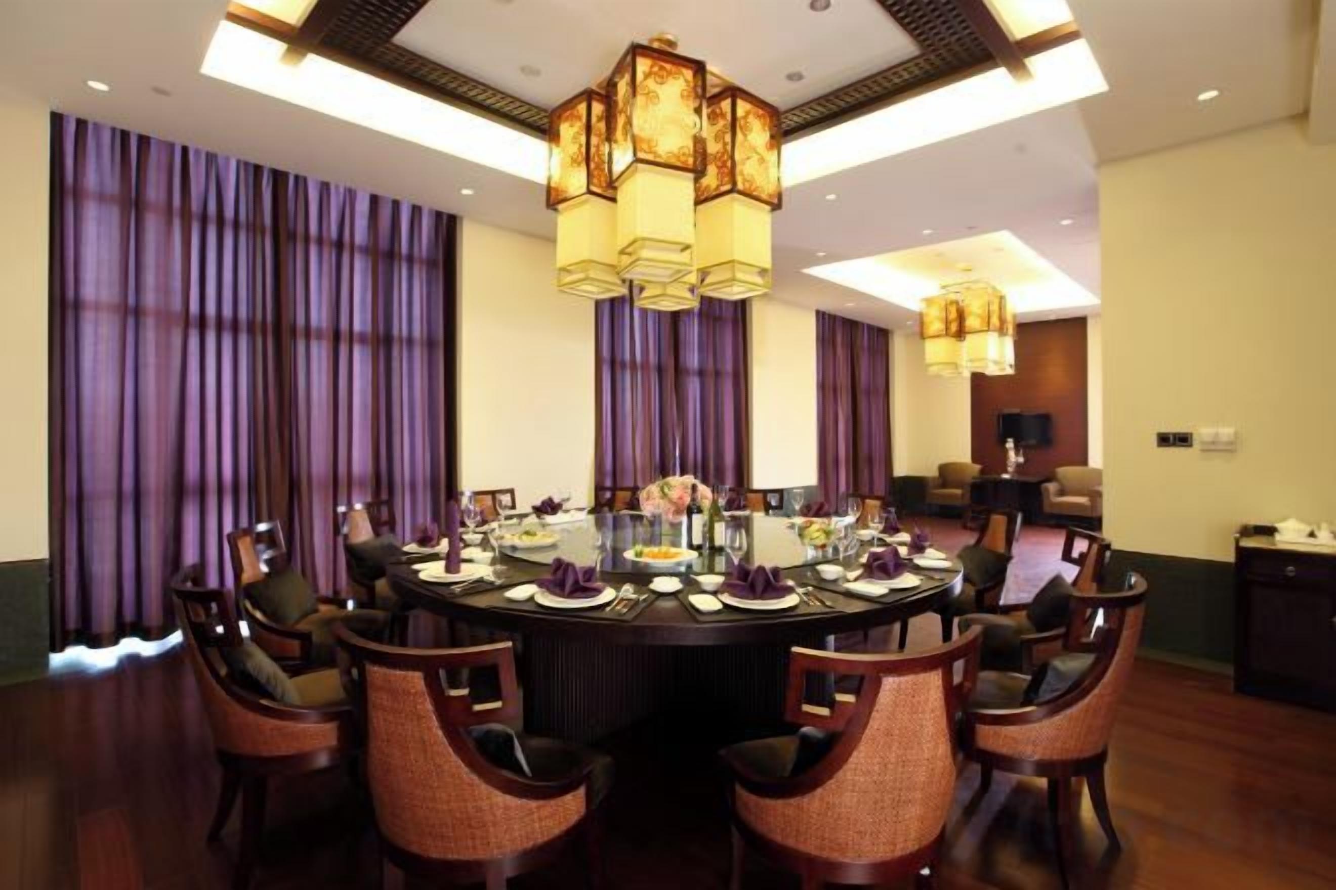 A conference room with a round table, chairs, and a chandelier.