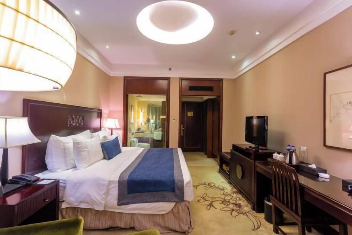 Een hotelkamer met een bed, een bureau, een televisie en een lamp.