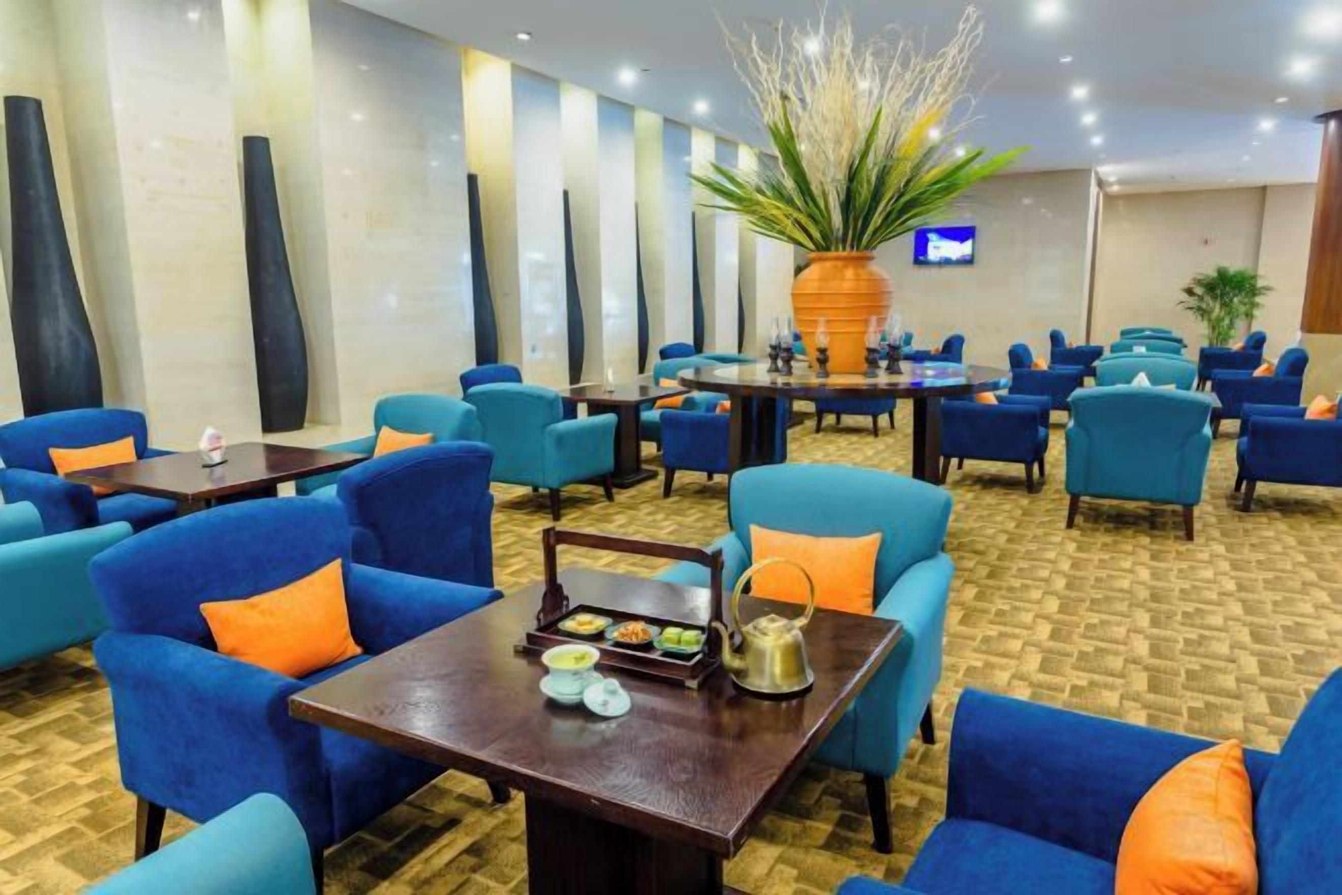 A hotel lobby with multiple seating areas, including sofas and chairs, arranged around tables.